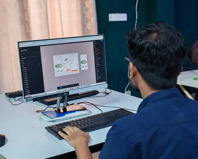 A designer building a website layout on a desktop monitor
